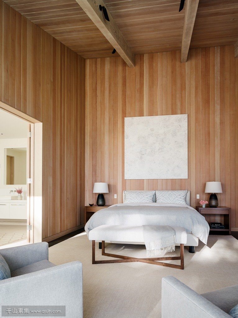 08-The-master-bedroom-features-comfortable-contemporary-furniture-and-much-wood-that-clads-the-walls-and-a-high-ceiling.jpg
