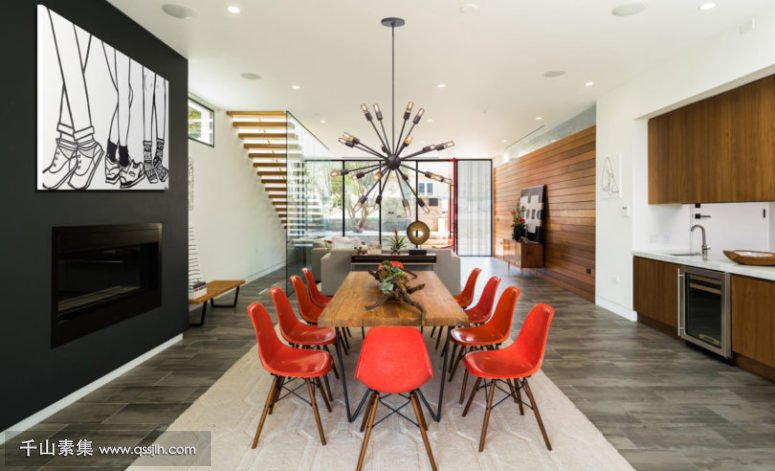06-The-dining-room-is-decorated-with-red-chairs-cool-wall-art-and-a-statement-chandelier-775x471.jpg