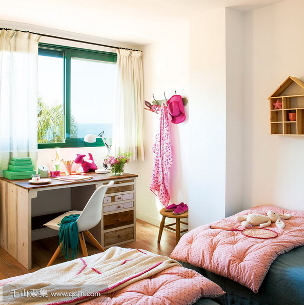 05-The-kids-room-is-done-with-bold-green-and-pink-theres-a-large-window-to-bring-light-in-and-two-beds.png