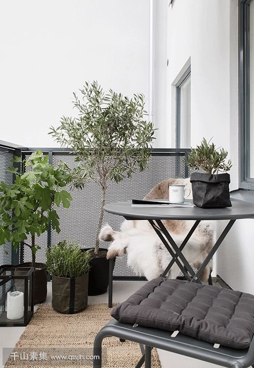 17-a-dark-metal-folding-furniture-set-potted-greenery-and-flowers-candle-lanterns-for-a-Scandinavian-feel.jpg