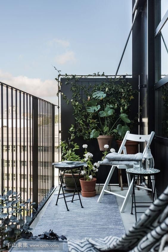 16-a-black-balcony-done-with-a-couple-of-folding-chairs-and-a-small-coffee-table-plus-a-lot-of-greenery-around.jpg