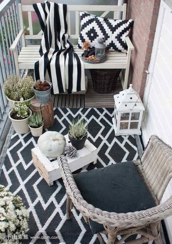 11-a-monochromatic-balcony-with-wicker-and-wooden-furniture-black-and-white-textiles-potted-plants-and-candle-lanterns.jpg