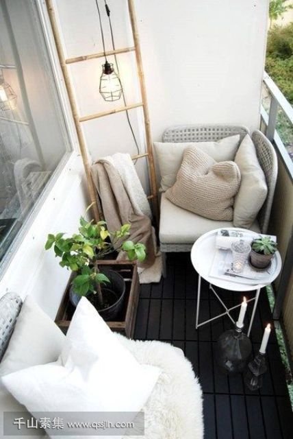 02-a-black-and-white-balcony-with-two-cofy-wicker-seats-a-coffee-table-candles-and-a-ladder-for-storage.jpg