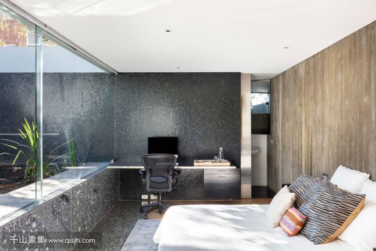 06-The-master-bedroom-shows-off-dark-stone-and-tile-walls-a-weathered-wood-wall-and-a-comfy-bed-plus-a-working-space-775x517.jpg